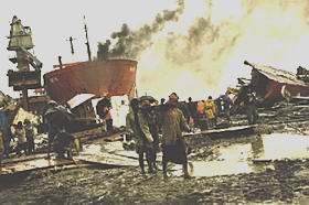 Barefoot workers walk amid scrap scattered at a Sitakunda ship-breaking yard where safely rules are hardly maintained.